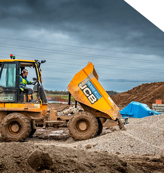 A forward tipping dumper unloading building material into a large pile.